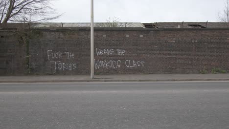 Cars-drive-past-an-anti--government-graffiti-on-a-brick-wall