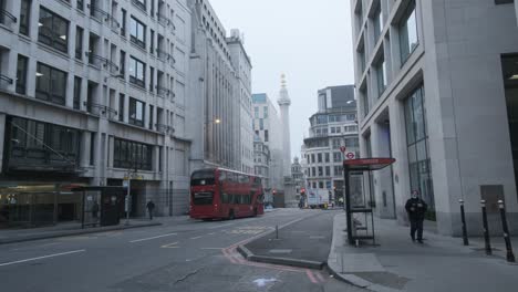 London-double-decker-buses-driving-down-gracechurch-street-monument-on-foggy-winter-morning