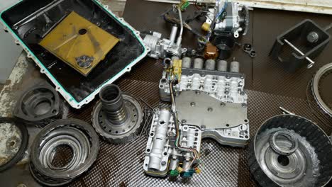 A-top-down-view-of-a-mechanics-workbench-showcasing-parts-of-a-transmission-torn-apart-on-it