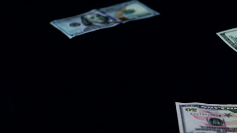 Billetes-De-Dólar-Arrojados-Lentamente-Y-Esparcidos-Sobre-Una-Superficie-Negra