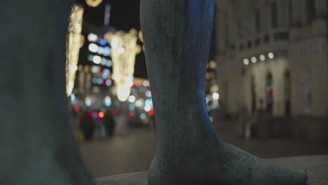 Statue-foots-and-blurred-background-of-street-decorated-with-Christmas-lights