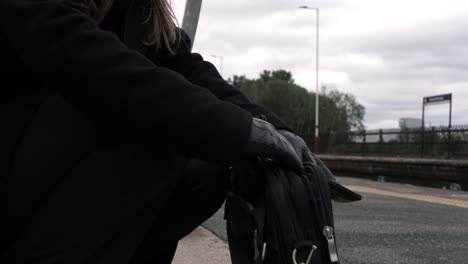 Business-woman-looking-in-briefcase-on-train-platform-medium-shot