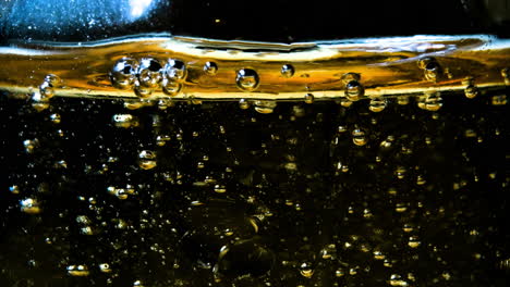 Abstrakte-Goldene-Flüssigkeit-Mit-Aufsteigendem-Blasenmuster-Auf-Dunklem-Hintergrund