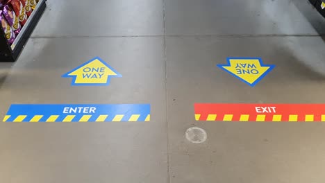 COVID-19-COVID-Coronavirus-Corona-one-way-enter-and-exit-stickers-and-arrows-on-concrete-floor-of-store-during-pandemic