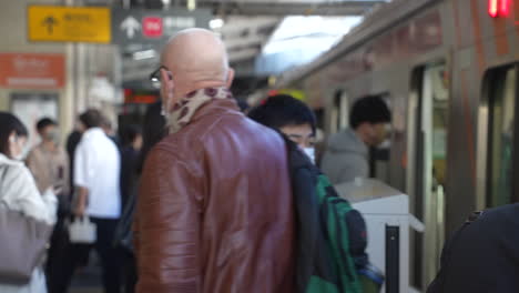 Szene-Am-Bahnhof-Mit-Passagieren-Mit-Gesichtsmaske,-Die-Inmitten-Einer-Pandemie-In-Tokio,-Japan,-In-Den-Zug-Ein--Und-Aussteigen