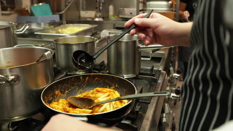 Chef-Adding-A-Ladle-Of-Broth-To-Penne-Pasta-In-A-Pan---close-up,-slow-motion