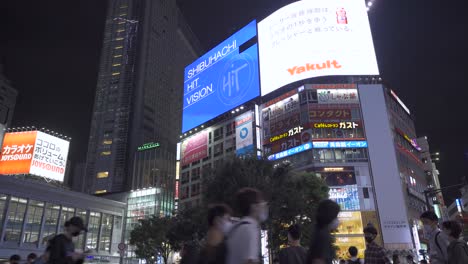 Sideways-POV-walking-across-busy-Shibuya-scramble-at-night---low-angle-upwards-view