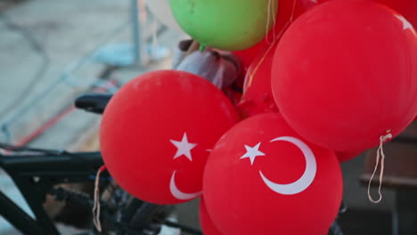 Bunte-Punch-Ballons-Für-Kinder-Und-Rote-Ballons-Mit-Türkischer-Flagge-Sind-An-Einem-Fahrrad-Befestigt,-Das-Auf-Der-Straße-Zum-Verkauf-Steht