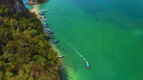 longtail-boat-driving-away-from-island,-thailand,-aerial,-camera-tilt