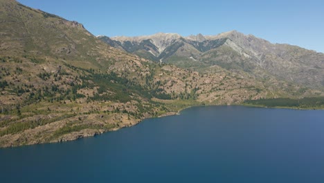 Aerial-dolly-in-of-Epuyen-lake-beside-Andean-mountains-with-pine-tree-forest,-Patagonia-Argentina