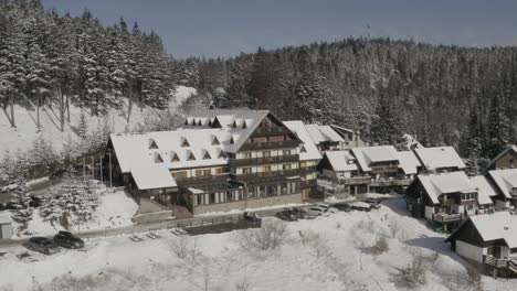 Lukov-Dom-winter-resort-with-cabins-aside-from-Kope-ski-run,-Aerial-pan-left-reveal-shot
