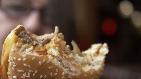 Woman-holding-out-cheese-burger-with-bites-taken-out-close-up-shot