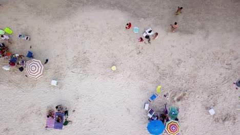 Luftaufnahme-Von-Familien-Mit-Kindern-Und-Sonnenschirmen,-Die-Den-Strand-Von-Bombas-In-Brasilien-Genießen