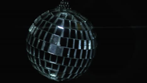 Small-rotating-disco-ball-with-reflected-moving-rays,-Anamorphic-lens-flare,-close-up-shot,-abstract-background-concept