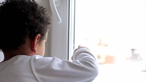 Little-boy-drawing-on-window-wet-with-condensation-stock-video-stock-footage
