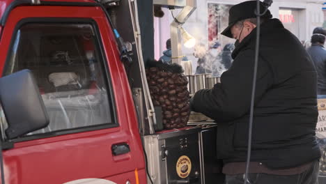 Male-Vendor-Packing-Cooked-Chestnuts-In-His-Mobile-Truck-Store-During-Winter