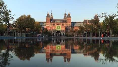 Sunset-time-lapse-of-the-art-museum-in-Amsterdam-with-people-passing-by-and-the-scene-reflected-in-the-water-pond-in-the-foreground