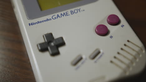 Panning-Extreme-Close-Up-of-the-Original-Nintendo-Game-Boy-on-a-Wooden-Table