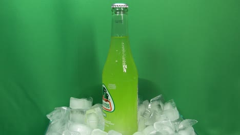 3-3-Botellas-De-Bebida-De-Lima-Jarritos-Que-Giran-360-Grados-Sobre-Hielo-Apilado-Frente-A-Una-Pantalla-Verde