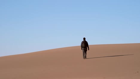Man-walking-on-sand-dunes-in-slow-motion