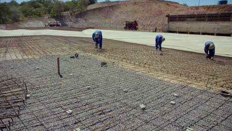 On-a-large-project,-men-tie-the-rebar-grid-in-position-before-pouring-the-foundation