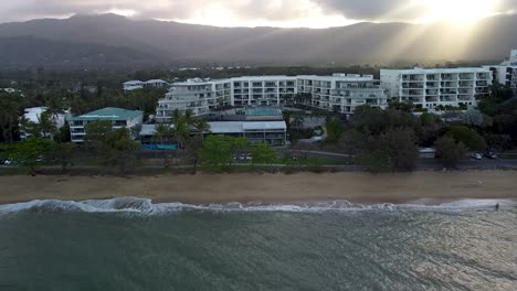 Aerial-Over-Trinity-Beach-And-Hotel-Resort-With-Sun-Breaking-Through-Clouds