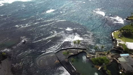 Rising-aerial-view-of-resort-with-sea-water-pool-by-ocean-in-Hawaii