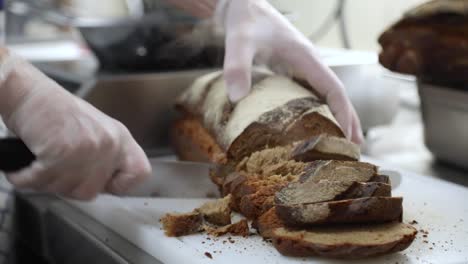 Slicing-Hot-Freshly-Baked-Loaf-Of-Bread-In-The-Kitchen-With-A-Bread-Knife---zoom-out,-slow-motion