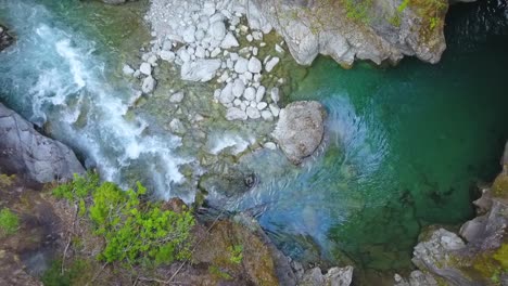 Aerial-top-down-dolly-out-of-Rio-Azul-stream-flowing-between-rocky-cliffs-surrounded-by-vegetation,-El-Bolsón,-Patagonia-Argentina