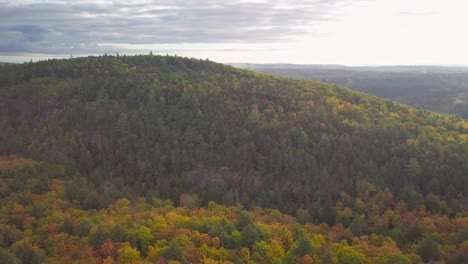 Weitwinkelaufnahme-Aus-Der-Luft-Tagsüber,-Die-über-Die-Farben-Des-Herbstwaldes-Fliegt-Und-Einen-Riesigen,-Hohen-Felskamm-Und-Nebel-In-Kawarthas,-Ontario,-Kanada,-Umkreist