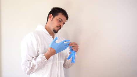 Doctor-in-PPE-suit-putting-on-blue-latex-gloves
