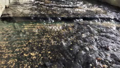 Gold-is-separated-from-black-sediment-in-sluice,-close-up-shot