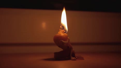 Eine-Deformierte-Kerze-Brennt-Im-Dunkeln