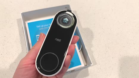 Hand-unboxing-a-Hello-nest-smart-wi-fi-home-security-camera-from-the-box-and-holding-up-the-device