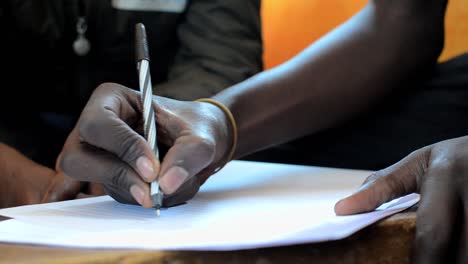 Close-up-of-hand-of-young-man-writing-in-a-seminar-in-Kibera,-Nairobi,-Kenya-1