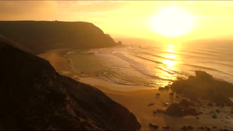 Flying-close-along-the-dark-mountains-cliffs-turning-tiliting-shot-overview-over-praia-de-castelejo-beach-cape-sagres-portugal,-with-rocks,-at-stunning-golden-sunset-with-epic-cinematic-style