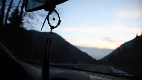 beautiful-handmade-dreamcatcher-moving-inside-of-a-car-in-a-mountain-road-at-sunset