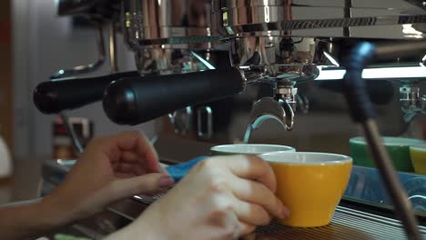 SLOWMO---Professional-female-barista-putting-cappuccino-porelain-cups-under-coffee-machine-portafilter