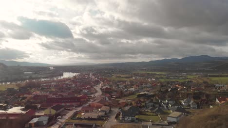 Rising-Aerial-Drone-over-beautiful-sunny-small-village-with-big-high-clouds-and-river
