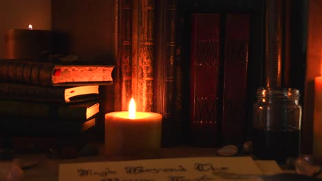 Close-up-background-of-an-ancient-library,-next-to-a-frieplace,-with-old-books,-a-feather,-old-paper,-ink,-stones,-and-candles-with-flickering-flames