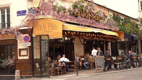 Menschen-Sitzen-Und-Essen-Vor-Einem-Café-In-Der-Nähe-Einer-Belebten-Pariser-Straße