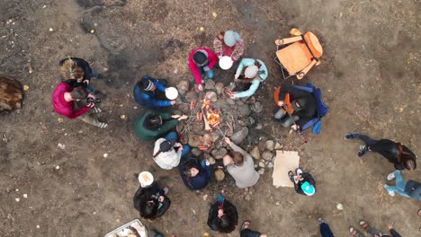 Aerial-view-of-young-people-roasting-hot-dogs-over-campfire-during-a-camping-trip