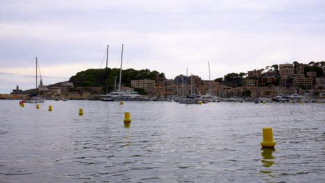 Boats-lying-in-the-small-marina-of-Port-D’Sóller,-Mallorca,-with-mountains-and-forest-in-the-background