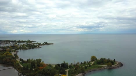 Aerial-view-of-the-Scarborough-Bluffs,-Canada,-with-a-smooth-down-drone-movement-and-the-panorama-of-Lake-Ontario