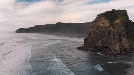 Flying-over-surfing-ocean-waves-at-Piha-Beach,-New-Zealand