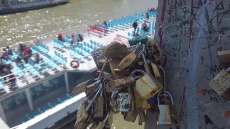 Love-lockers-on-a-bridge-with-blurry-tour-boat-passing-under