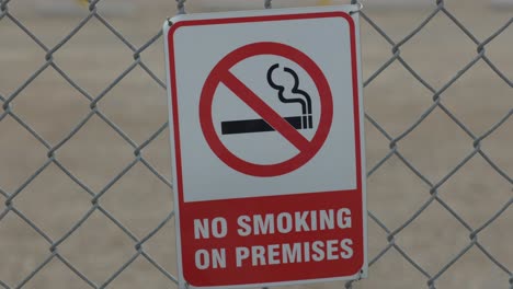 A-quick-zoom-in-on-a-red-and-white-no-smoking-sign-that-is-behind-a-chain-linked-fence