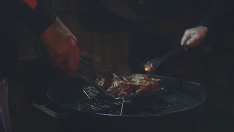 Two-men-move-cuts-of-lamb-around-the-barbeque-together-with-tongs