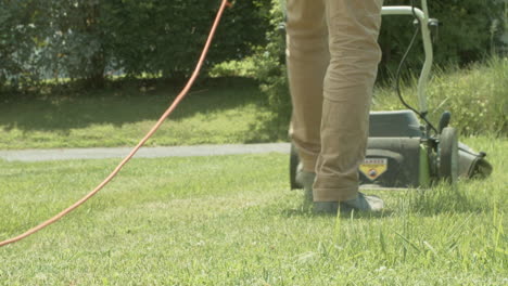 Man-walks-away-mowing-grass-with-electric-lawnmower