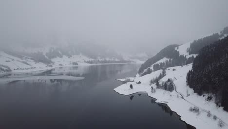 Camera-flight-through-snowfall-on-a-beautiful-mountain-lake-in-Switzerland